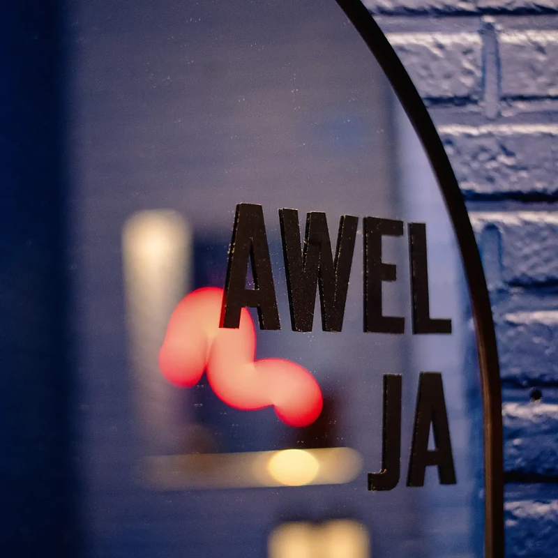 Het opschrift AWEL JA op een ronde spiegel voor een blauwe bakstenen muur