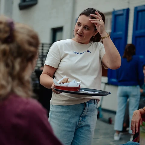 Natalie met een dienblad tussen de gasten op het terras