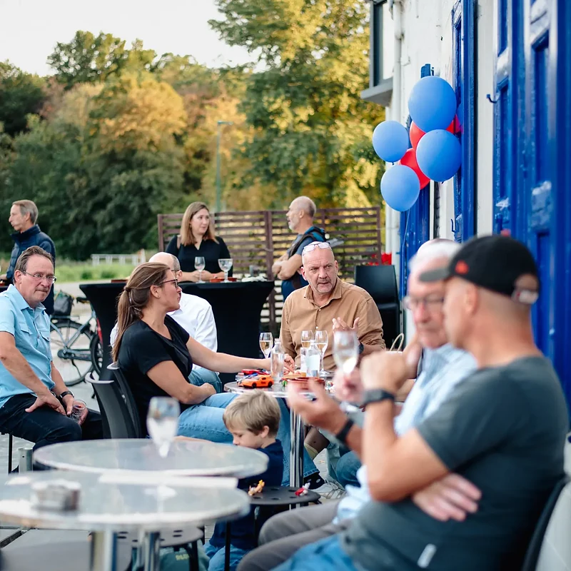 Het terras naast de blauwe luiken, met de bomen van het Zoet Water erachter
